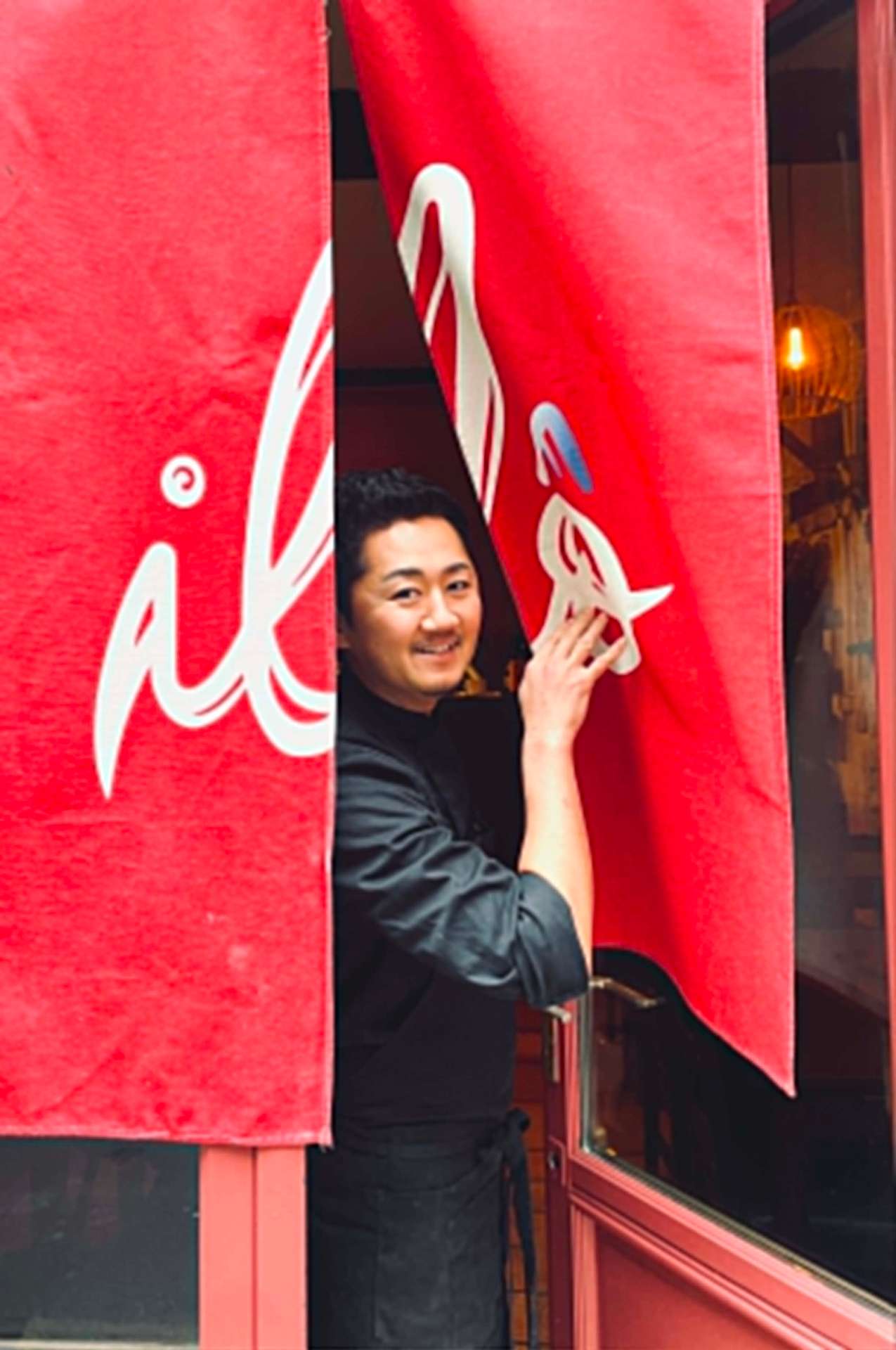 Tatsuya Ozeki regarde par le noren du restaurant Ilô